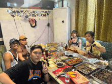 a group of people are sitting around a table with food and a pizza box that says ' beef ' on it