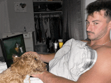 a man laying in bed with a dog looking at a laptop screen