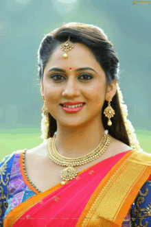 a woman wearing a gold necklace and earrings is smiling