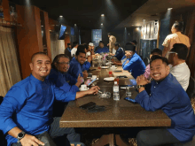 a group of men in blue shirts are sitting at a table in a restaurant