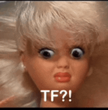 a doll with big eyes and red lips is making a funny face and says tf ?