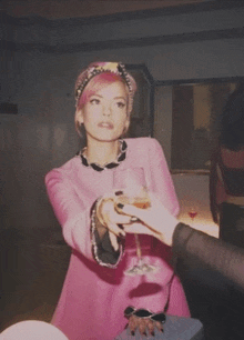 a woman in a pink dress is holding a wine glass