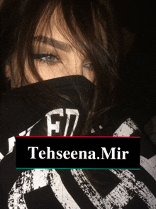 a woman covering her face with a black shirt that says tehseena mir