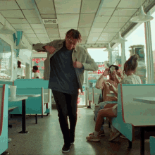 a man is dancing in a diner with a sign on the wall that says ' a ' on it