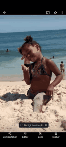 a little girl in a bikini is kneeling in the sand on the beach