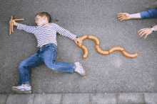 a boy is laying on the ground with sausages in the shape of a wave