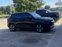 a black suv is parked in a parking lot next to a silverado truck