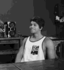 a black and white photo of a man wearing a white tank top