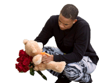 a man is kneeling down holding a teddy bear and roses