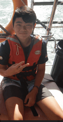 a young man wearing a sola life vest giving a peace sign