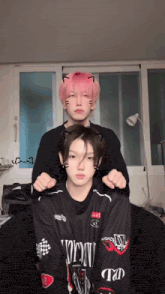 a boy with pink hair is sitting next to another boy