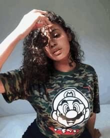 a woman wearing a camouflage shirt with a mario on it