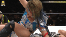 a woman in a blue and silver outfit is wrestling another woman in a black outfit