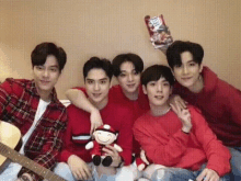 a group of young men are posing for a picture while one of them is holding a stuffed animal