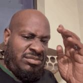 a bald man with a beard is holding something in his hand and making a face