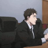 a man in a suit and tie sits at a table
