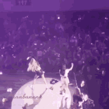 a group of people are dancing on a stage in a purple room .