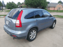 a blue honda crv is parked in a parking lot with a house in the background