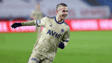 a soccer player wearing a yellow and blue jersey with avis on it is running on a field .