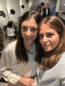 two women posing for a picture in a room