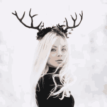 a woman with white hair is wearing a headband with deer antlers .