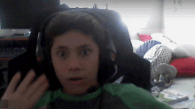 a young boy wearing headphones and a green shirt is making a surprised face