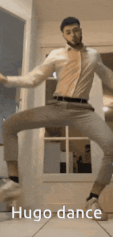 a man in a white shirt and gray pants is dancing with the caption hugo dance