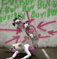 a mascot is crawling on the ground in front of a brick wall with graffiti .