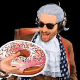 a man wearing a wig and sunglasses is holding a donut with sprinkles
