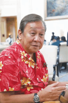 a man wearing a red shirt with flowers and a watch on his wrist