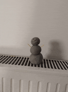 a snowman made out of clay is sitting on top of a radiator