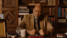 a man sits at a desk with a white mug that says " let 's keep a conversation going " on it