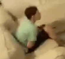 a blurry picture of a man sitting on a couch in a bathroom .