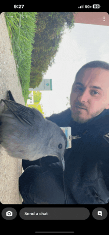 a man holding a bird in front of a sign that says send a chat