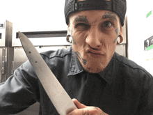 a man with a tattoo on his face is holding a knife and making a funny face