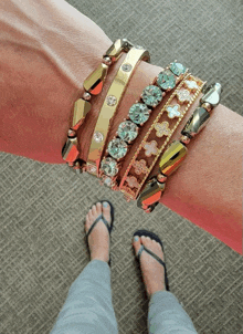 a woman 's wrist with a stack of bracelets including one that has a cross on it