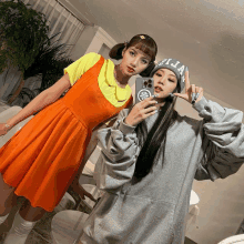 a girl in an orange dress takes a selfie with another girl