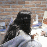 a woman sitting at a desk with a stack of books on it and a sign that says ' a ' on it