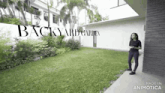 a woman is standing in a backyard garden in front of a white building .