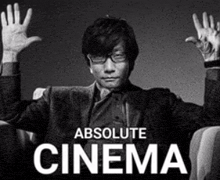 a man in a suit is sitting in a chair with his hands up in the air .