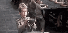 a young boy is holding a bowl of food in his hands .