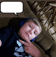 a boy wearing headphones is laying on a couch with a speech bubble above him