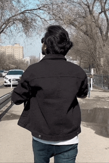 a man wearing a black jacket is walking down the street