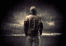 a man in a hoodie stands in the rain