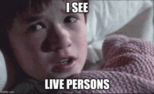 a young boy is laying in bed with a pink blanket and a meme that says `` i see live people '' .