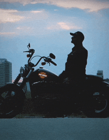 a man sits on a harley davidson motorcycle on the side of the road