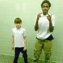 two boys are standing next to each other in front of a green wall