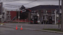 a blurry picture of a street with a building in the background and a few orange cones in the foreground