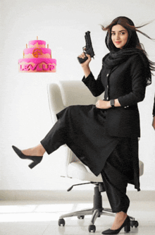 a woman sitting on a chair holding a gun in front of a cake that says leav life