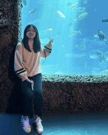 a girl sitting in front of an aquarium with fish